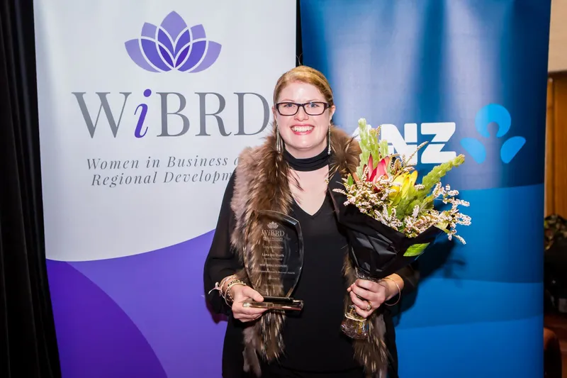 Lana-Joy Durik holding the Best Small Business award and flowers at the WIBRD awards event